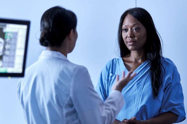 Woman patient talking to healthcare professional with image scans at the back