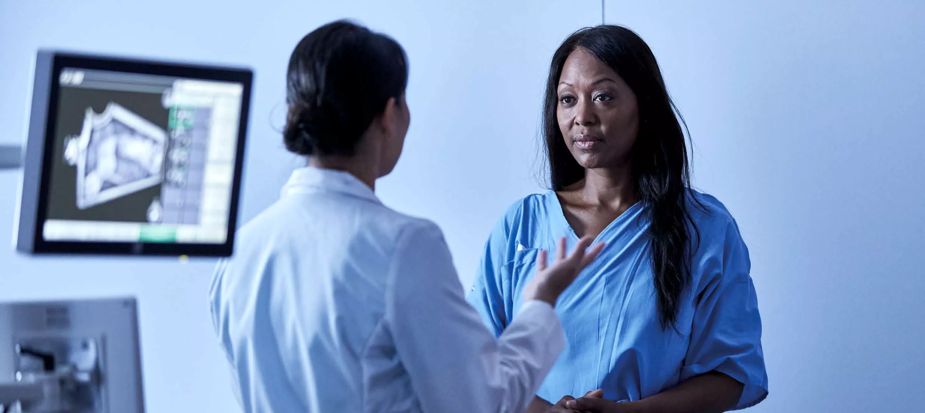 Woman patient talking to healthcare professional with image scans at the back